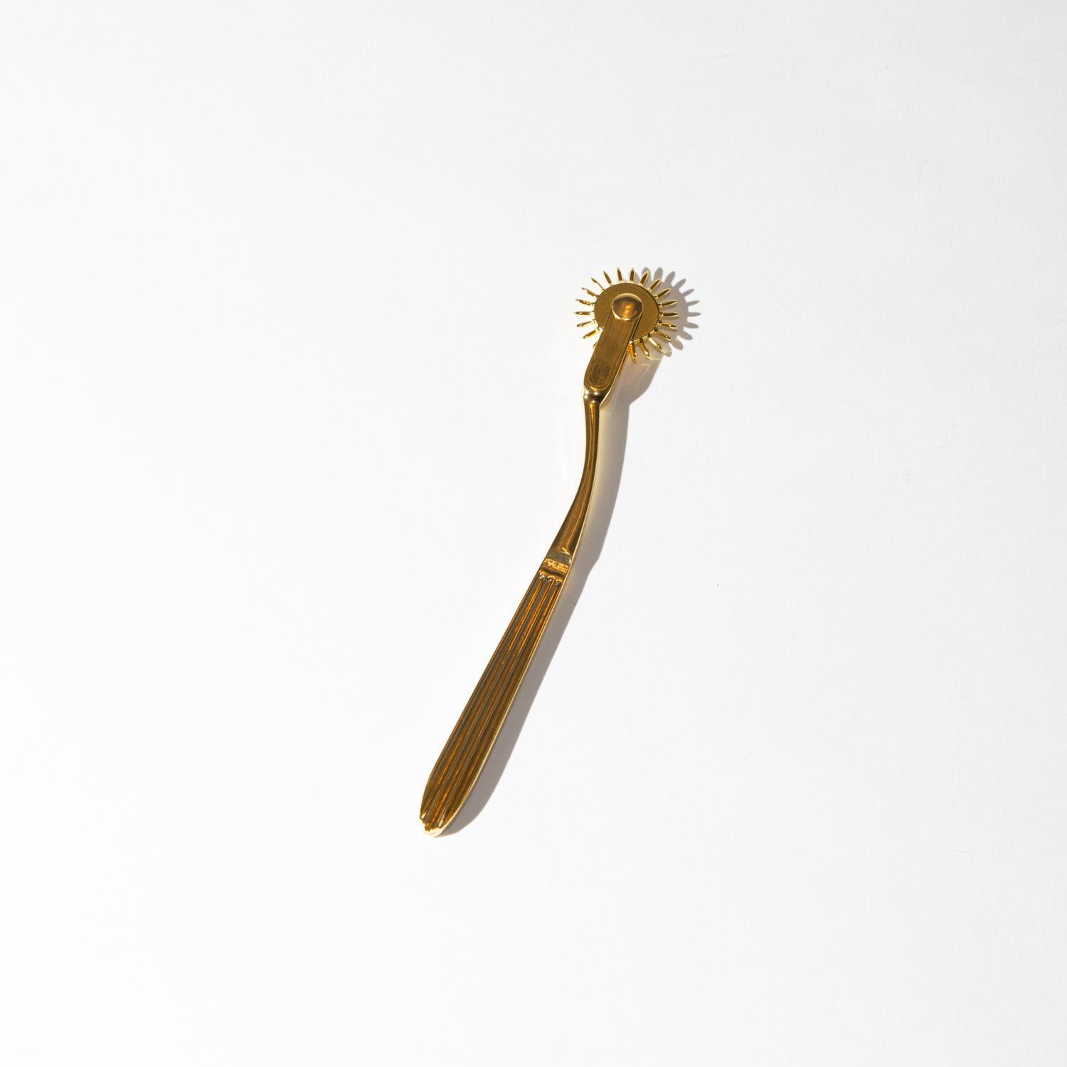 Gold-colored wartenberg wheel on a white background