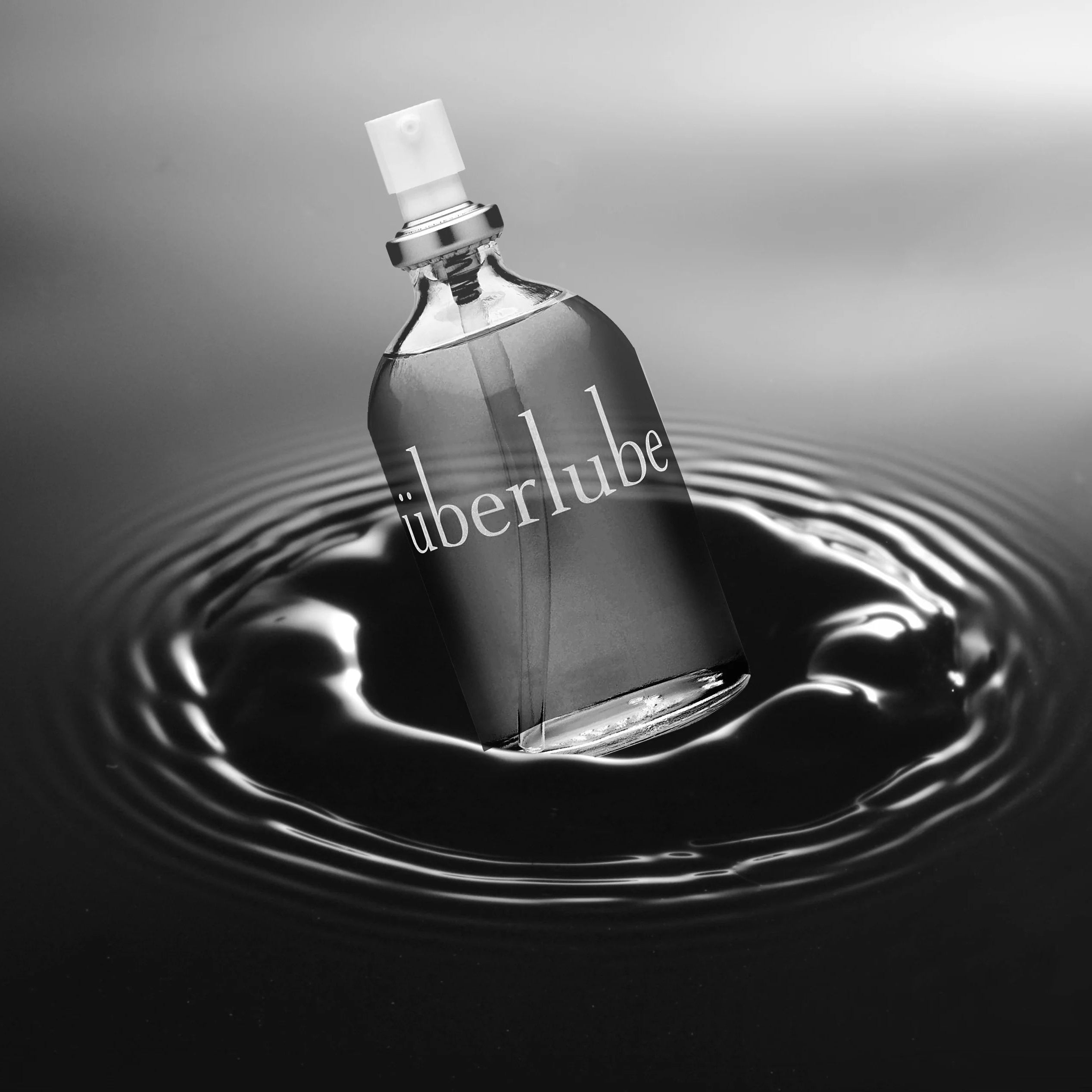 Uberlube bottle floating on water with a gray background